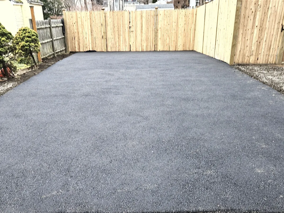 Newly paved asphalt parking area between new wood fences